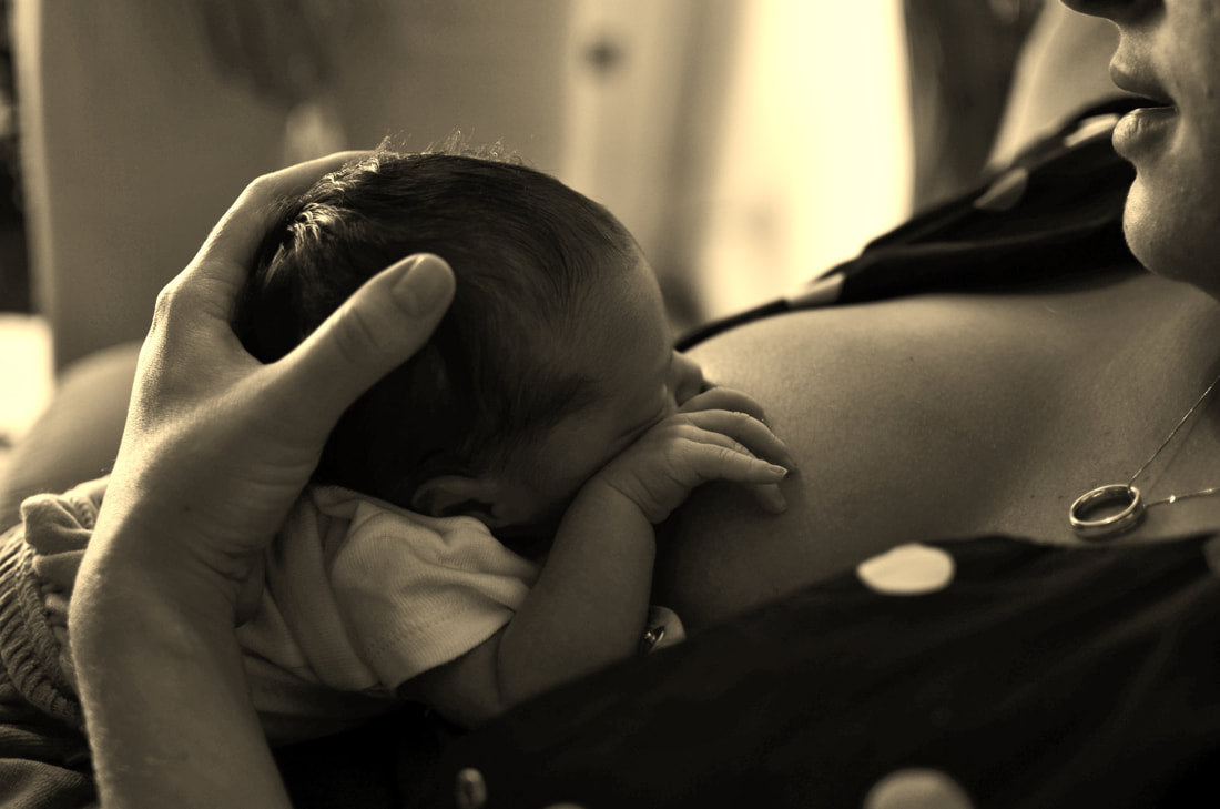 Mom breastfeeding baby in the laid back position | Metopolitan Breastfeeding